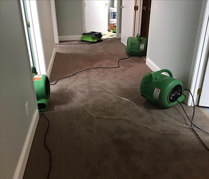 Hallway with brown carpet wet with water with SERVPRO drying equipment