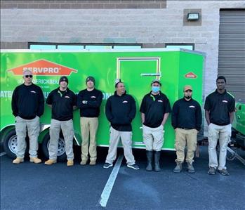 Group of male technicians and crew chiefs standing in front of green background