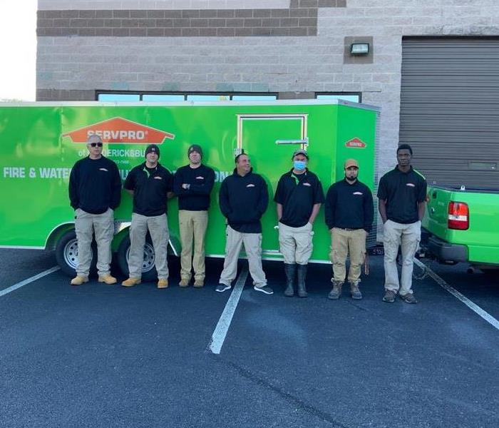 Group of SERVPRO team members standing in front of green trailer