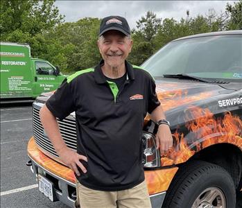SERVPRO Employee standing outside next to a wrapped SERVPRO truck in a parking lot