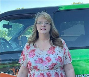 SERVPRO Employee standing outside next to a wrapped SERVPRO truck in a parking lot